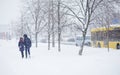 Abstract blurred people silhouettes walking along snowy street in winter. Heavy snowfall in the city. Blurred image of mother and
