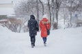 Abstract blurred people silhouettes walking along snowy street in winter. Heavy snowfall in the city. Blurred image of a two girls