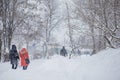 Abstract blurred people silhouettes walking along snowy street in winter. Heavy snowfall in the city. Blurred image of a two girls