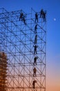 Silhouetted Men on metal stage scaffolding at dusk