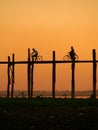 Silhouetted people with bikes on U Bein Bridge at sunset, Amarapura, Myanmar Royalty Free Stock Photo