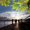 Silhouetted people walking on street over sunset sky Royalty Free Stock Photo