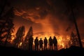 Silhouetted people witness forest fire at night