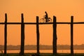 Silhouetted person on with a bike on U Bein Bridge at sunset, Am