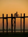 Silhouetted person on with a bike on U Bein Bridge at sunset, Am