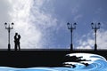 Silhouetted young lovers on a seaside promenade