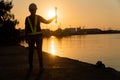 Silhouettes of asian woman engineer holding wrenches and standing on shipyard and background is oil storage silo. Concept of women Royalty Free Stock Photo