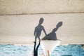 Silhouettes on the asphalt of the bride and groom who walk along the road by the sea holding hands Royalty Free Stock Photo