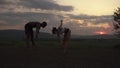 Silhouettes of athletic mixed race couple stretching together on the rocky mountains background. Sport fitness concept