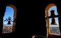Silhouettes backlit by the evening sun of two restored bronze bells of the Torre de la Clerecia with views of the city of