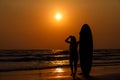 silhouettes of beautiful sexy young women surfer girls in bikinis with surfboards on a beach at sunset in sea, sport activity and Royalty Free Stock Photo