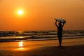 silhouettes of beautiful sexy young women surfer girls in bikinis with surfboards on a beach at sunset in sea, sport activity and Royalty Free Stock Photo