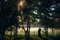 Silhouettes of bride and groom are kissing on the shore of lake between trees at sunset Royalty Free Stock Photo