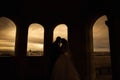 Silhouettes of bride and groom standing on night city background and tenderly looking at each other at sunset Royalty Free Stock Photo