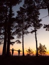 Silhouettes of brother and sister on the pine coast in evening time