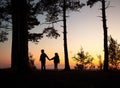 Silhouettes of brother and sister on the pine coast of the sea