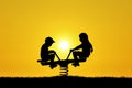 Silhouettes of brother and sister on playground swings