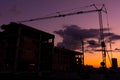 Silhouettes of building cranes at construction site. Real estate buildings at sunset Royalty Free Stock Photo