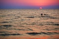 Silhouettes of children playing in the waves at sunset
