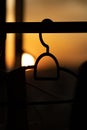 Silhouettes of clothes hangers on a metal bar with a golden sun at sunset in the background Royalty Free Stock Photo