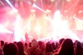 Silhouettes of concert and people crowd in front of bright stage lights and blurry people on stage