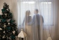 Silhouettes of a couple in love, a man and a woman, standing with their backs near a large window behind a curtain Royalty Free Stock Photo