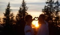 Silhouettes of couple in love at sunset gesturing heart Royalty Free Stock Photo