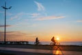 Silhouettes of a couple riding on bikes in sea side park