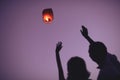 silhouettes of couple waving hands to flying sky lantern