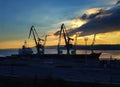 Silhouettes of cranes and ships at the port at sunset