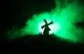 Silhouettes crowd of hungry zombies and old windmill on hill against dark foggy toned sky. Silhouettes of scary zombies walking at Royalty Free Stock Photo