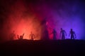 Silhouettes crowd of hungry zombies and old windmill on hill against dark foggy toned sky. Silhouettes of scary zombies walking at