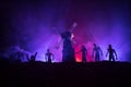 Silhouettes crowd of hungry zombies and old windmill on hill against dark foggy toned sky. Silhouettes of scary zombies walking at