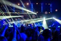 Silhouettes of crowds of spectators at a concert with smartphones in their hands