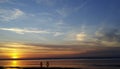 Silhouettes of cyclists at sunset of the day on the sandy bank of the river. Riding on bicycles on the water. Royalty Free Stock Photo