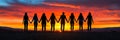 Silhouettes of Eight People Holding Hands in Front of a Vivid Sunset, Copy Space Available Royalty Free Stock Photo