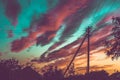 Silhouettes of an electric pole, a house and trees against a blue sunset sky with red clouds Royalty Free Stock Photo