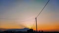 silhouettes of electric poles around the rice fields against the backdrop of mountains and a golden sunset Royalty Free Stock Photo