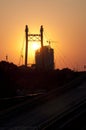 Silhouettes of electricity pylon structure, construction site and bridge road at sunset Royalty Free Stock Photo