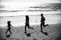 Silhouettes of family jogging along sea beach at sunrise. Outdoor workout, silhouettes of runners, sport and healthy