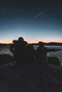 Silhouettes of a family sitting on the cooastline rock looking at the sea at sunset