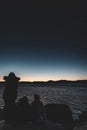 Silhouettes of a family sitting on the cooastline rock looking at the sea at sunset