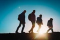 Silhouettes of family with two kids hiking in sunset mountains