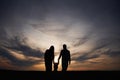 Silhouettes of father, mother and little baby son is outdoors against sunset dramatic sky in the field Royalty Free Stock Photo