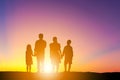 Silhouettes of father mother son and daughter playing and relaxing at sunset evening sky background