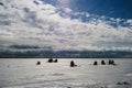 Silhouettes of fishermen fishing and snowmobile in winter on the ice