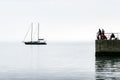 Silhouettes of fishermen on the pier on the background of the silhouette of a yacht on the calm sea Royalty Free Stock Photo