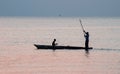 Silhouettes of fishermen sailing in a wooden boat at sunset Royalty Free Stock Photo