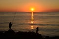 Silhouettes of fishers on sea cliff at sunrise Royalty Free Stock Photo