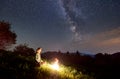 Silhouettes of girl near haystack and bonfire under starry sky on which Milky Way is visible Royalty Free Stock Photo